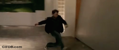 A Man In A Black Jacket Is Kneeling Down In A Hallway . GIF