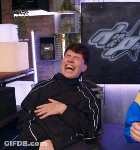 A Man In A Black Jacket Is Laughing In Front Of A Sign That Says ' Altitude ' GIF