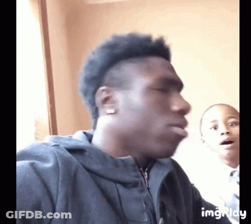 A Man In A Black Jacket Is Making A Funny Face While A Boy Looks On GIF