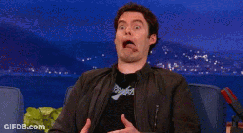 A Man In A Black Jacket Is Making A Funny Face While Sitting In A Chair . GIF