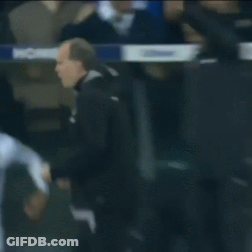 A Man In A Black Jacket Is Pointing At Something In Front Of A Crowd . GIF