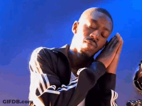 A Man In A Black Jacket Is Praying With His Hands Folded . GIF