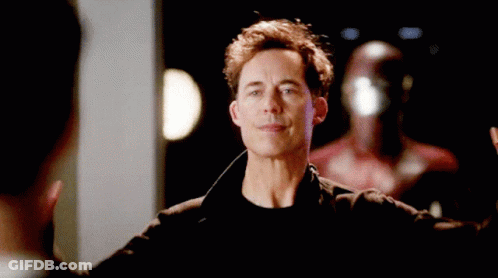 A Man In A Black Jacket Is Raising His Hands In The Air . GIF