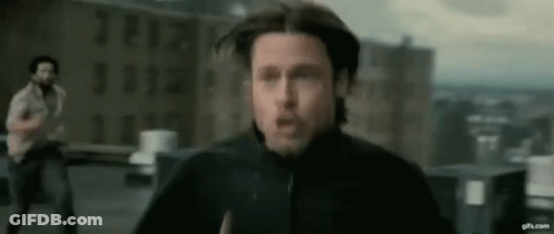 A Man In A Black Jacket Is Running On A Rooftop While Another Man Looks On . GIF
