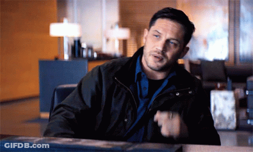 A Man In A Black Jacket Is Sitting At A Table Talking GIF