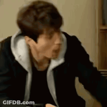 A Man In A Black Jacket Is Sitting At A Table With His Mouth Open . GIF