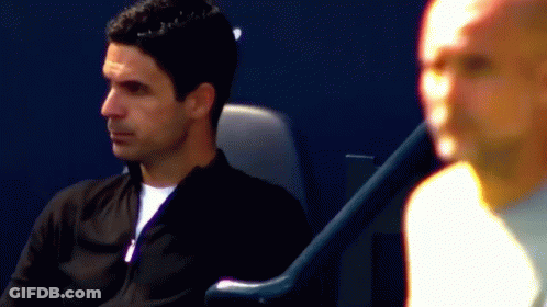 A Man In A Black Jacket Is Sitting In A Chair GIF