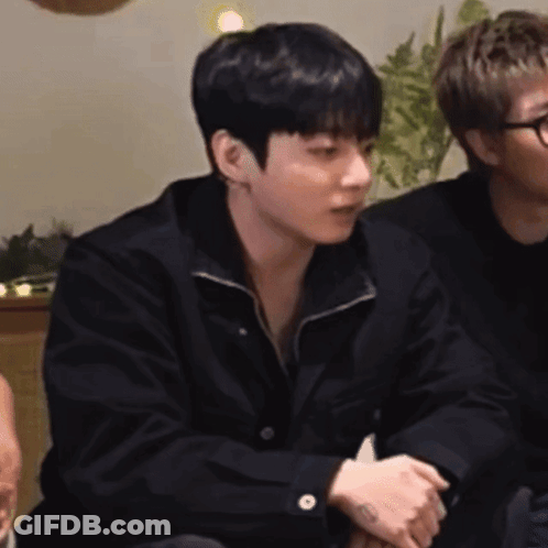 A Man In A Black Jacket Is Sitting Next To Another Man In A Black Shirt . GIF