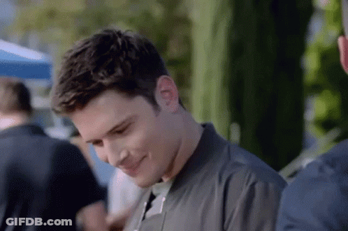 A Man In A Black Jacket Is Smiling While Standing Next To Another Man . GIF