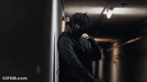 A Man In A Black Jacket Is Standing In A Dark Room GIF
