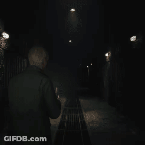 A Man In A Black Jacket Is Standing In A Dark Room GIF