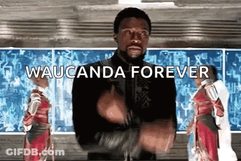 A Man In A Black Jacket Is Standing In Front Of A Chalkboard With The Words Waucunda Forever Written On It . GIF
