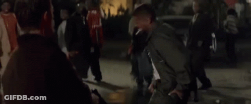 A Man In A Black Jacket Is Standing In Front Of A Crowd Of People And Says You Motherfucker . GIF