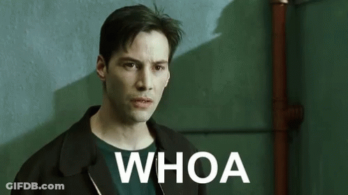 A Man In A Black Jacket Is Standing In Front Of A Green Wall With The Words `` Whoa '' Written On It . GIF