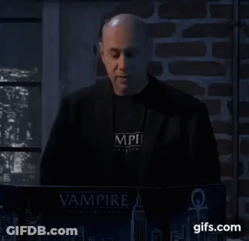 A Man In A Black Jacket Is Standing In Front Of A Laptop Computer . GIF