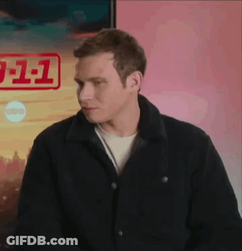 A Man In A Black Jacket Is Standing In Front Of A Poster That Says 911 GIF