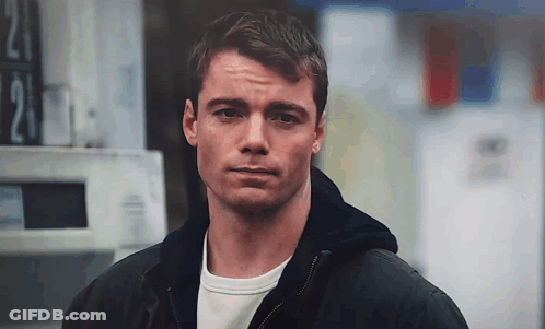 A Man In A Black Jacket Is Standing In Front Of A Sign That Says 21 . GIF