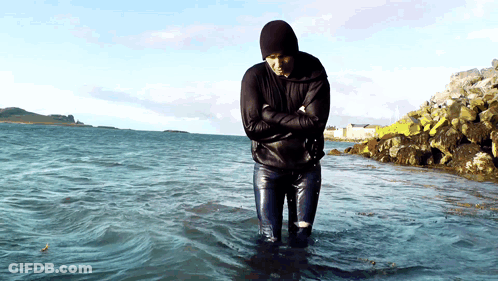 A Man In A Black Jacket Is Standing In The Water GIF