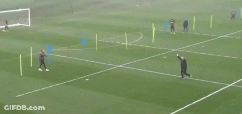A Man In A Black Jacket Is Walking On A Soccer Field With Another Man GIF