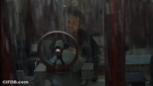 A Man In A Black Jacket Looks Out A Window GIF