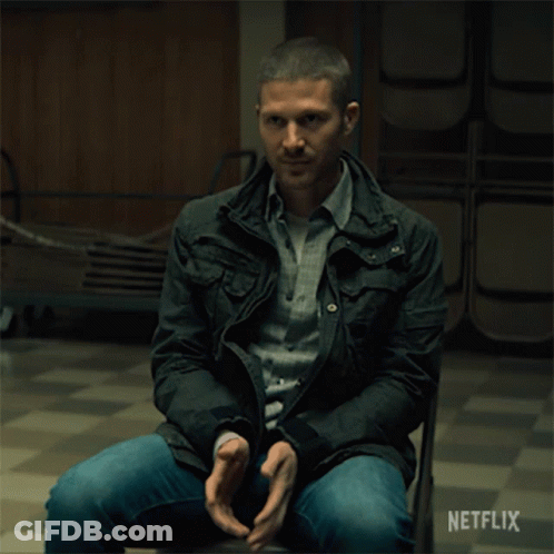 A Man In A Black Jacket Sits In A Chair With A Netflix Logo On The Bottom GIF