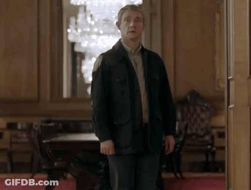 A Man In A Black Jacket Standing In A Room GIF