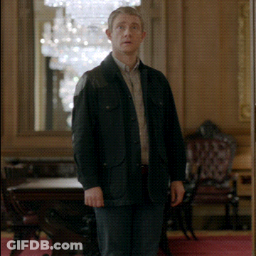A Man In A Black Jacket Stands In A Room GIF