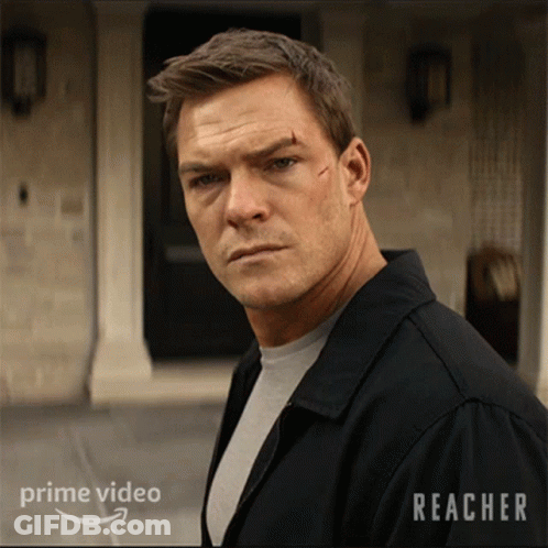 A Man In A Black Jacket Stands In Front Of A Building With Reacher Written On It GIF