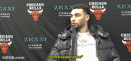 A Man In A Black Jacket Stands In Front Of A Chicago Bulls Backdrop GIF