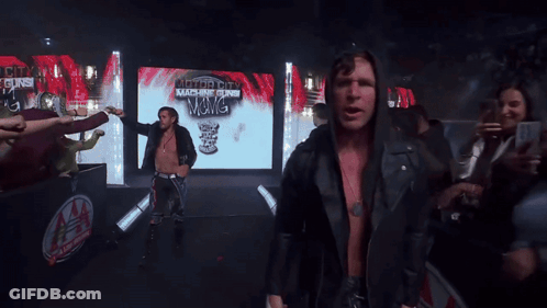 A Man In A Black Jacket Stands In Front Of A Screen That Says Authority Machine Gun GIF