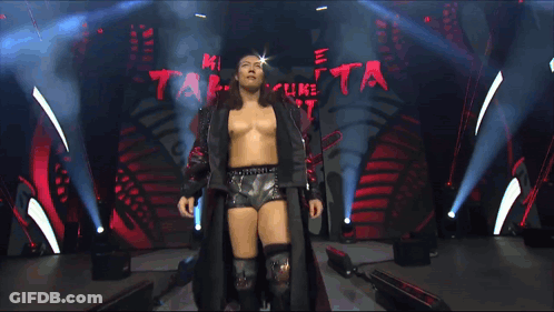 A Man In A Black Jacket Stands In Front Of A Sign That Says Grand Slam On It GIF