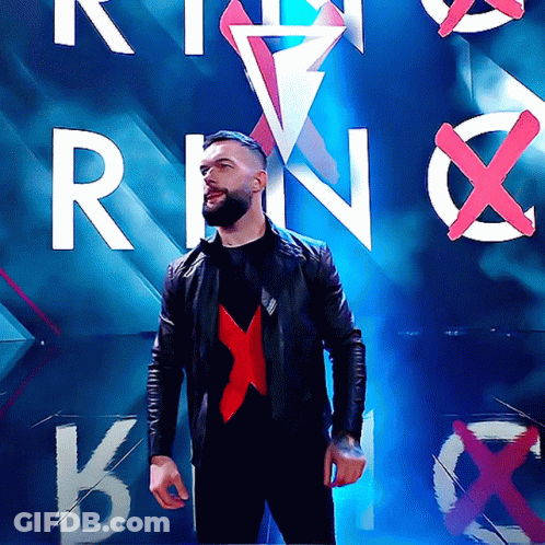 A Man In A Black Jacket Stands In Front Of A Wall With The Letters R And N On It GIF