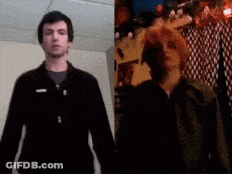 A Man In A Black Jacket Stands Next To Another Man GIF