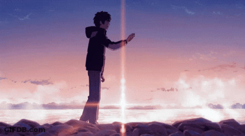 A Man In A Black Jacket Stands On A Rocky Shoreline GIF