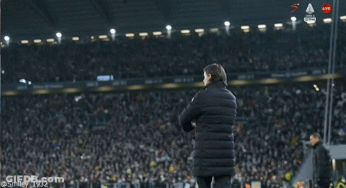 A Man In A Black Jacket Stands On A Soccer Field In Front Of A Banner That Says Intesa GIF