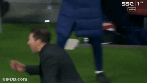 A Man In A Black Jacket Stands On A Soccer Field With Ssc In The Corner GIF