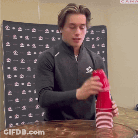 A Man In A Black Jacket With A Maple Leaf On It Stacks Red Cups GIF
