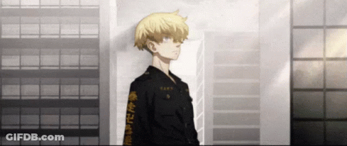 A Man In A Black Jacket With Chinese Writing On The Sleeves Stands In Front Of A Building . GIF