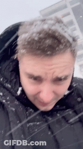 A Man In A Black Jacket With Snow On His Hair GIF