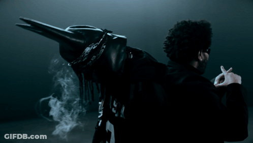 A Man In A Black Jacket With The Letter P On The Back Is Smoking A Cigarette GIF
