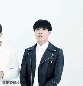 A Man In A Black Leather Jacket And White Shirt Is Standing Next To Another Man In A White Shirt . GIF