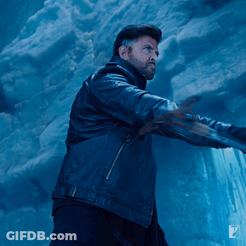 A Man In A Black Leather Jacket Is Standing In Front Of A Blue Wall GIF