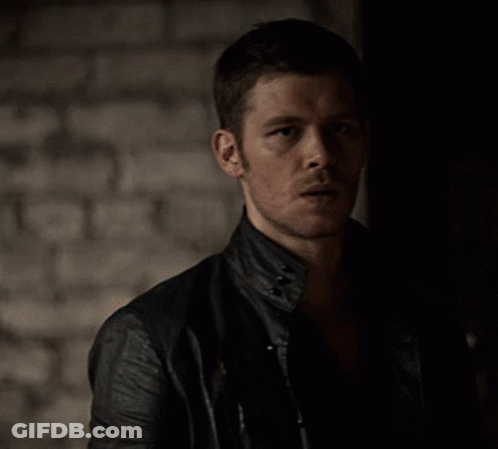A Man In A Black Leather Jacket Stands In The Dark GIF