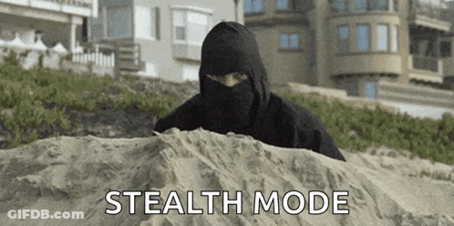 A Man In A Black Mask Is Hiding In The Sand . GIF