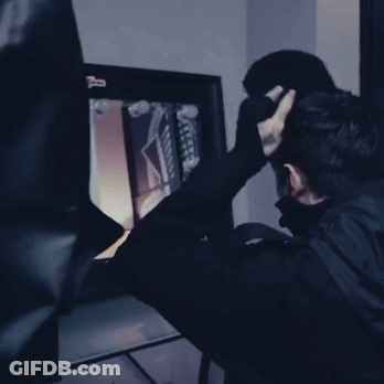 A Man In A Black Mask Is Looking At A Screen With A Sticker On It That Says ' X Ray ' GIF