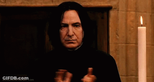 A Man In A Black Robe Is Standing In Front Of A Lit Candle And Giving A Thumbs Up . GIF