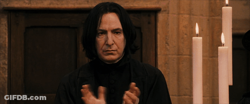 A Man In A Black Robe Stands In Front Of Candles GIF