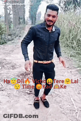 A Man In A Black Shirt And Black Pants Is Standing On A Dirt Path GIF