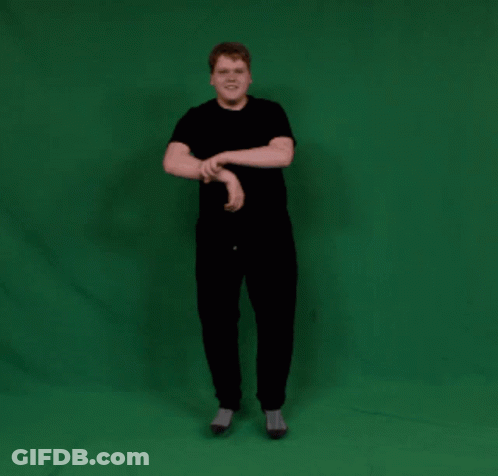 A Man In A Black Shirt And Black Pants Stands In Front Of A Green Screen GIF