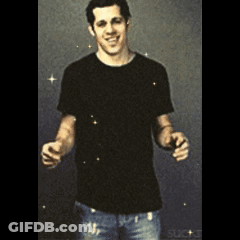 A Man In A Black Shirt And Jeans Is Standing With His Arms Outstretched And Smiling GIF